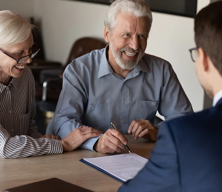 Elderly couple signing documents with their lawyer
